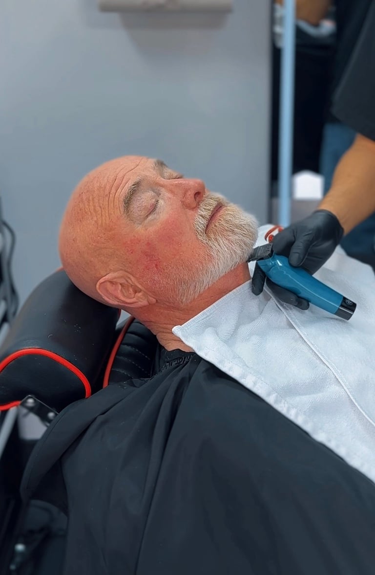 Older man receiving facial treatment with handheld device from practitioner wearing black gloves in clinical setting