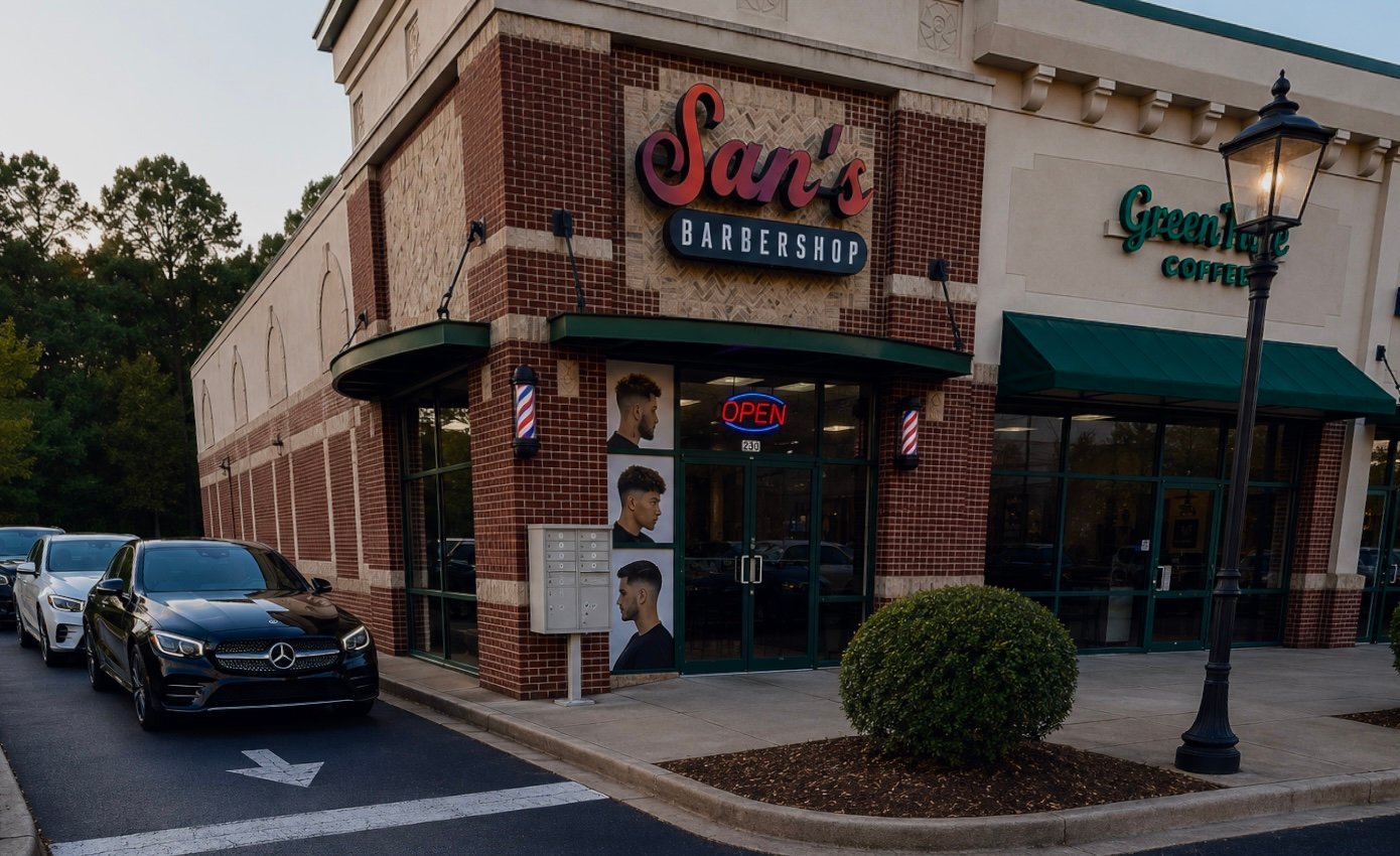 A brick barbershop storefront with red signage, street lamp, and parked car nearby.